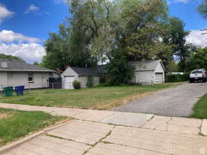 View of front of property with a garage, an outdoor structure, and a front yard