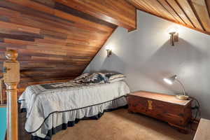 Carpeted bedroom featuring vaulted ceiling with beams and wood ceiling