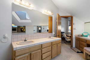 Bathroom featuring decorative backsplash, vanity, and lofted ceiling