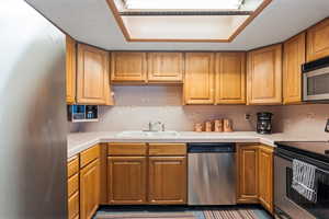 Kitchen with tile countertops, sink, appliances with stainless steel finishes, and tasteful backsplash