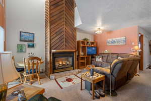 Living room featuring a tile fireplace, carpet, and a textured ceiling