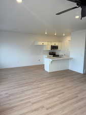 Kitchen with sink, appliances with stainless steel finishes, a breakfast bar, white cabinets, and light wood-type flooring