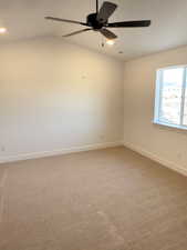 Carpeted spare room featuring ceiling fan and lofted ceiling