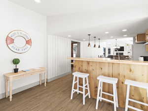 Kitchen with a breakfast bar, white fridge, kitchen peninsula, and light hardwood / wood-style floors