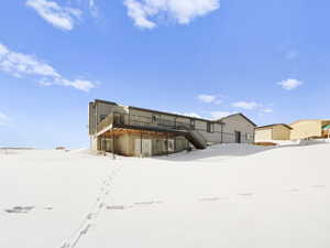 Snow covered rear of property with a deck