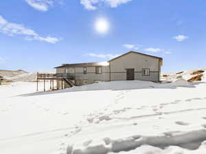 Snow covered back of property with a deck with mountain view