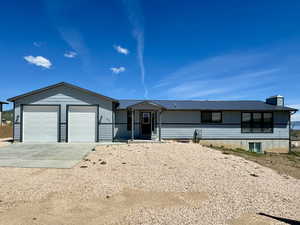 Ranch-style home featuring concrete driveway, a metal roof, an attached garage, and a chimney