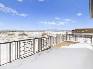 Yard covered in snow with a mountain view and a balcony