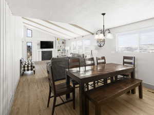 Dining space featuring lofted ceiling with beams, light hardwood / wood-style floors, built in features, and a wealth of natural light