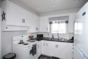 Kitchen featuring white cabinetry, decorative backsplash, laminate floors, white appliances, and sink