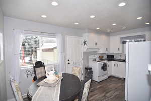 Dining and Kitchen area featuring white cabinetry and white appliances