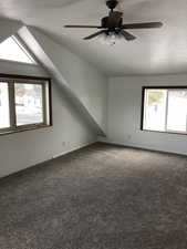 Bonus room with carpet, a textured ceiling, vaulted ceiling, and ceiling fan