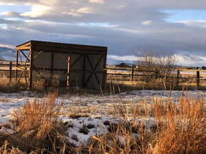 Snow covered structure with a mountain view and a rural view