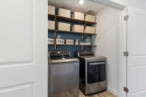 Clothes washing area featuring independent washer and dryer and light wood-type flooring