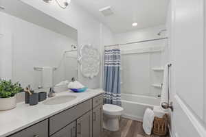 Full bathroom with hardwood / wood-style floors, vanity, shower / tub combo, and toilet