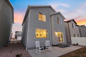 Back house at dusk featuring a patio area