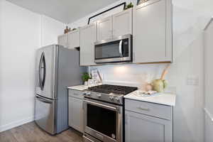 Kitchen with gray cabinets, hardwood / wood-style floors, and stainless steel appliances