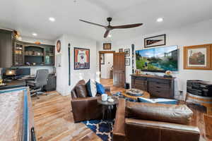 Living room featuring ceiling fan, built in desk, and light wood-type flooring