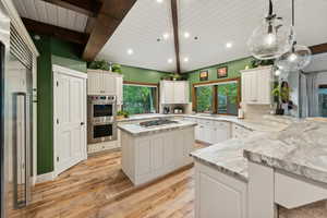 Kitchen featuring a center island, tasteful backsplash, light hardwood / wood-style flooring, decorative light fixtures, and appliances with stainless steel finishes