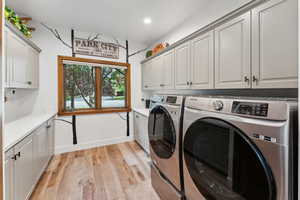 Washroom featuring cabinets, separate washer and dryer, and light hardwood / wood-style floors