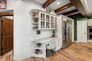 Kitchen with lofted ceiling with beams, light hardwood / wood-style flooring, appliances with stainless steel finishes, white cabinetry, and wood ceiling