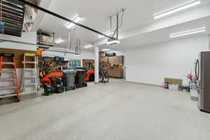 Garage featuring a garage door opener and stainless steel refrigerator