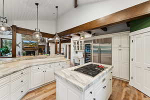 Kitchen featuring appliances with stainless steel finishes, a center island, decorative light fixtures, and a stone fireplace