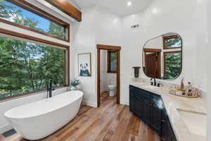 Bathroom with a bathing tub, vanity, wood-type flooring, and a towering ceiling