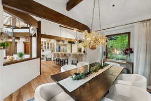 Dining room with vaulted ceiling with beams and light hardwood / wood-style floors