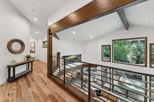 Hallway with light wood-type flooring, vaulted ceiling with beams, and wood ceiling