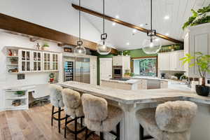 Kitchen featuring a kitchen breakfast bar, stainless steel appliances, pendant lighting, white cabinets, and a kitchen island