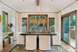 Dining space featuring hardwood / wood-style floors, lofted ceiling with beams, wooden ceiling, and a notable chandelier