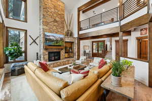 Living room with high vaulted ceiling, light wood-type flooring, a fireplace, and a wealth of natural light