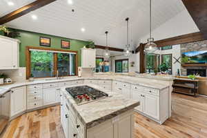 Kitchen featuring a stone fireplace, decorative backsplash, sink, and a kitchen island