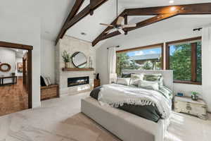 Bedroom with a fireplace, beam ceiling, multiple windows, and ceiling fan