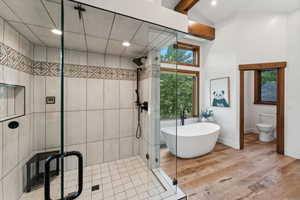 Bathroom featuring hardwood / wood-style floors, lofted ceiling with beams, toilet, and shower with separate bathtub