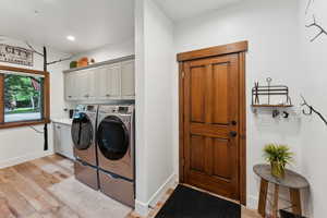 Laundry room featuring cabinets, independent washer and dryer, and light wood-type flooring