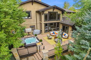 Back of house with an outdoor hot tub, an outdoor hangout area, and a deck