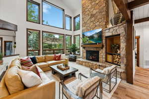 Living room with plenty of natural light, a fireplace, high vaulted ceiling, and light hardwood / wood-style flooring