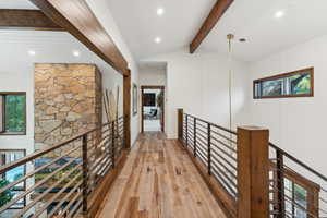 Hall with lofted ceiling with beams, light hardwood / wood-style flooring, and plenty of natural light