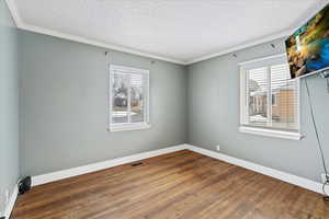 Unfurnished bedroom with a textured ceiling, hardwood / wood-style flooring, plenty of natural light, and crown molding