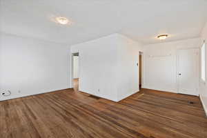 Unfurnished room featuring a textured ceiling and dark hardwood / wood-style flooring