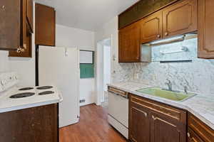 Kitchen with decorative backsplash, sink, light hardwood / wood-style floors, and white appliances