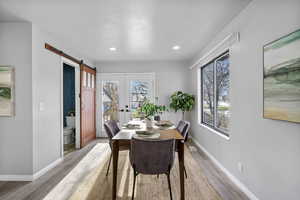 Dining room featuring light wood-type flooring, french doors, and a barn door