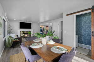 Dining space with a fireplace, light wood-type flooring, a barn door, and a healthy amount of sunlight