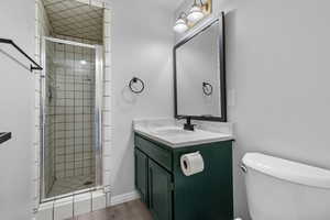 Bathroom with walk in shower, vanity, wood-type flooring, and toilet