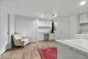 Kitchen featuring washer / clothes dryer, light hardwood / wood-style flooring, and white cabinets