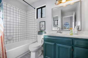 Full bathroom with hardwood / wood-style flooring, shower / bath combo with shower curtain, vanity, and toilet