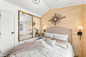 Bedroom with wood walls, lofted ceiling, crown molding, and a closet