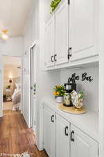 Bar featuring white cabinets, dark hardwood / wood-style floors, and crown molding